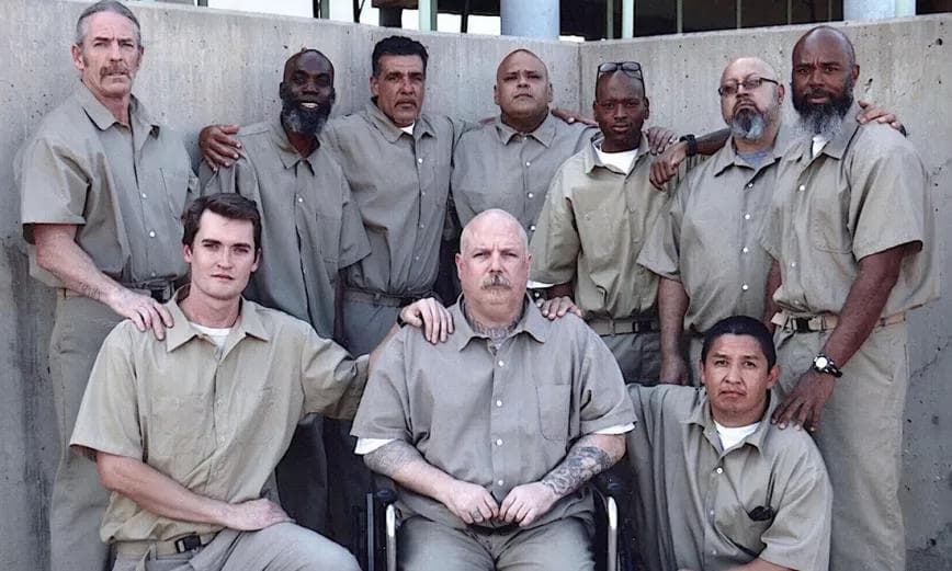A group photo of Ross Ulbricht with other inmates in a prison yard.